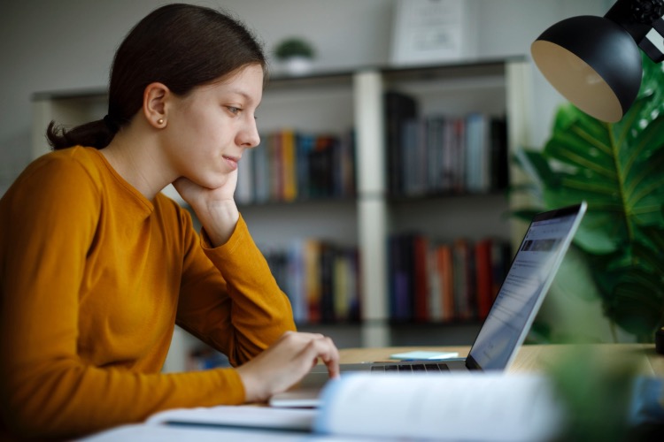 Mulher busca no computador a melhor opção de agência de tradução.